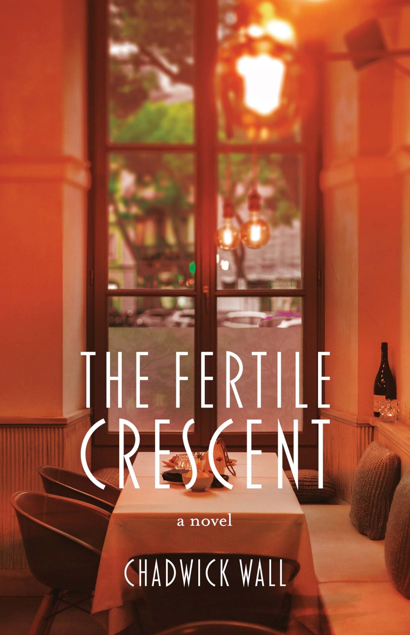 A warmly lit restaurant with a set dining table, cozy chairs, and a wine bottle on the bench evokes the charm of the Fertile Crescent. Large windows reveal a blurred green outdoor scene. Text on image: The Fertile Crescent, a novel, Chadwick Wall.