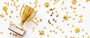 A gold trophy surrounded by star confetti, representing awards and recognition.