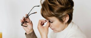 A tired author removing glasses, symbolizing reflection and pausing.